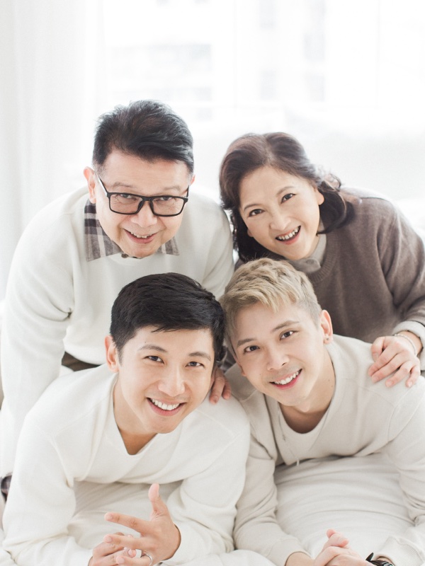 Izac and his family smiling together in a bright studio portrait.